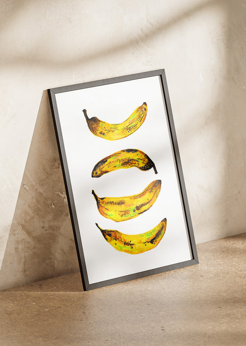 Framed artwork of four bananas in various stages of ripeness on a neutral background